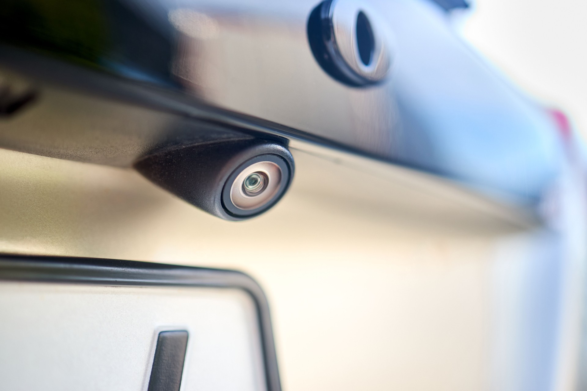Luxury car rear view camera for parking assistance selective focus close up with sunflare and copyspace. Concept of safety car driving while parking process. Assist device equipment in modern cars.