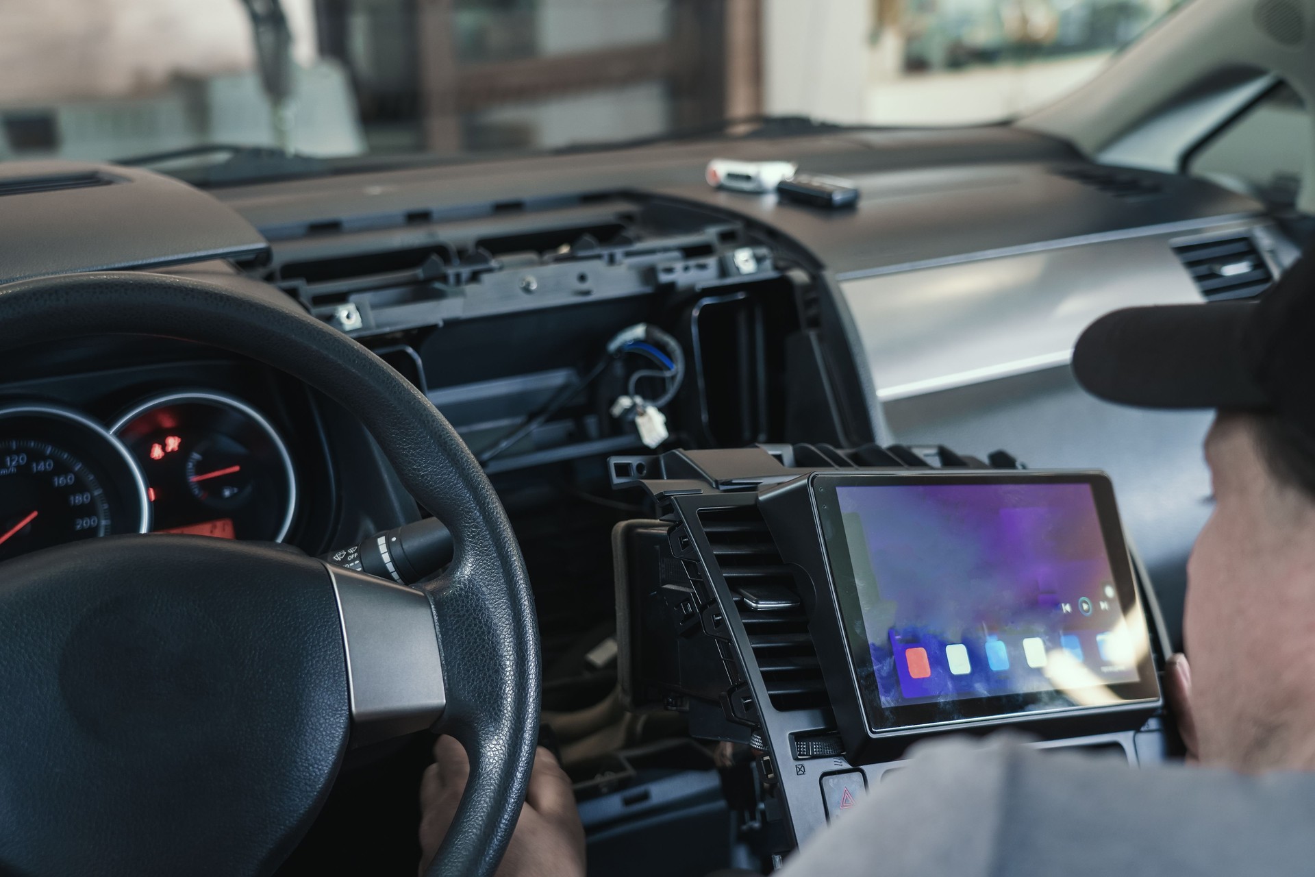 Auto electrician or repairman in car service installs multimedia sound system or car radio in auto dashboard panel